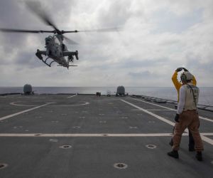 U.S. Navy sailors signal to a Marine Corps AH-1Z Viper attack helicopter from Marine Light Attack Helicopter Squadron 367 as it takes off from the flight deck of USS Canberra (LCS 30) during Navy-Marine Corps integration operations in the Philippine Sea on October 1, 2026.