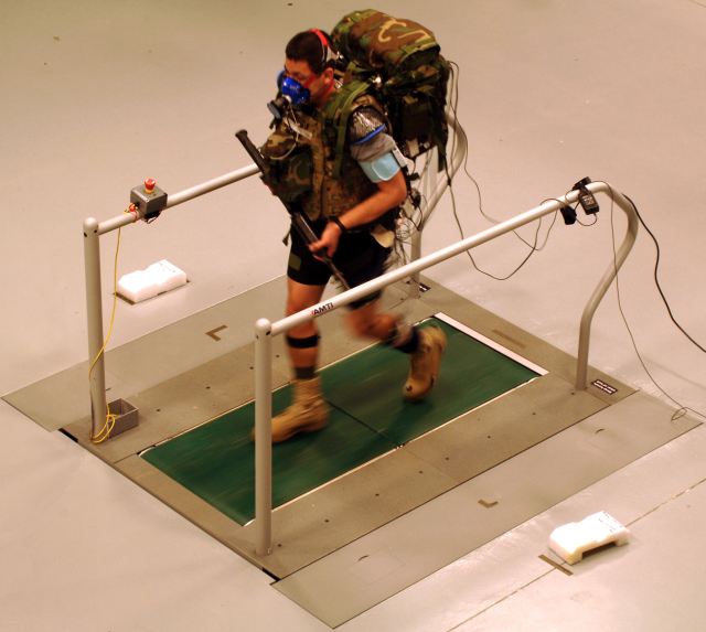 A Soldier carries a 28 kg load while walking in a prototype DARPA Warrior Web system during an independent evaluation by the U.S. Army. Warrior Web seeks to create a soft, lightweight under-suit that would help reduce injuries and fatigue common for Soldiers, who often carry 45 kg loads for extended periods over rough terrain. 