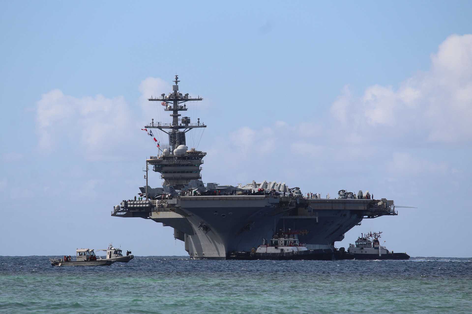 Harbor tugboats assist U.S. Navy Nimitz-class aircraft carrier USS Abraham Lincoln (CVN 72) as it arrives at Naval Base Guam for a scheduled port visit on December 11, 2025.