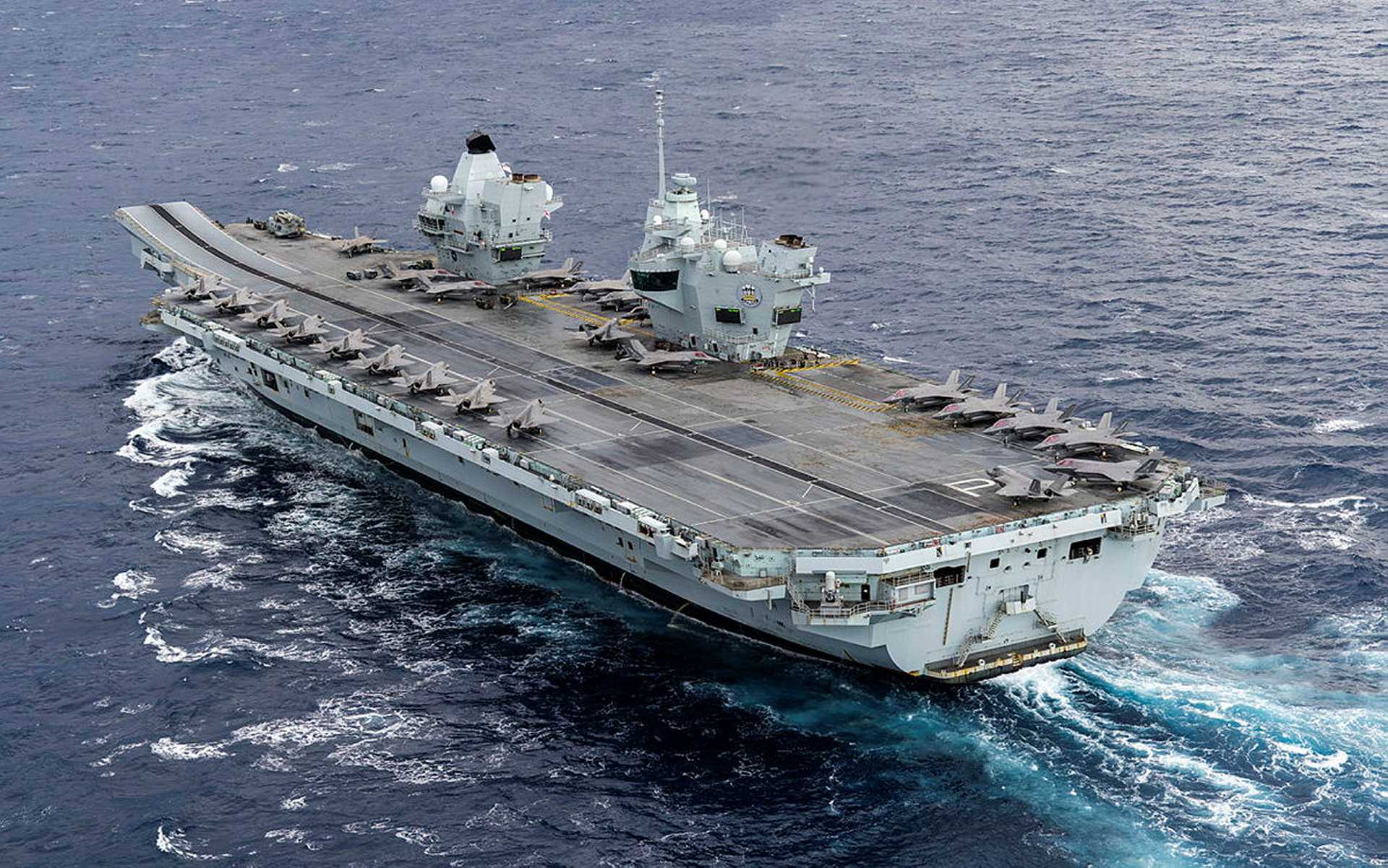 View of 24 British and Italian F-35B Lightning II jets positioned on the flight deck of HMS Prince of Wales. Marking the full operating capability of the United Kingdom Carrier Strike Group, this deployment features the largest fifth-generation carrier air wing ever embarked on a British aircraft carrier. The combined air wing supports NATO operations during Neptune Strike 25-4.