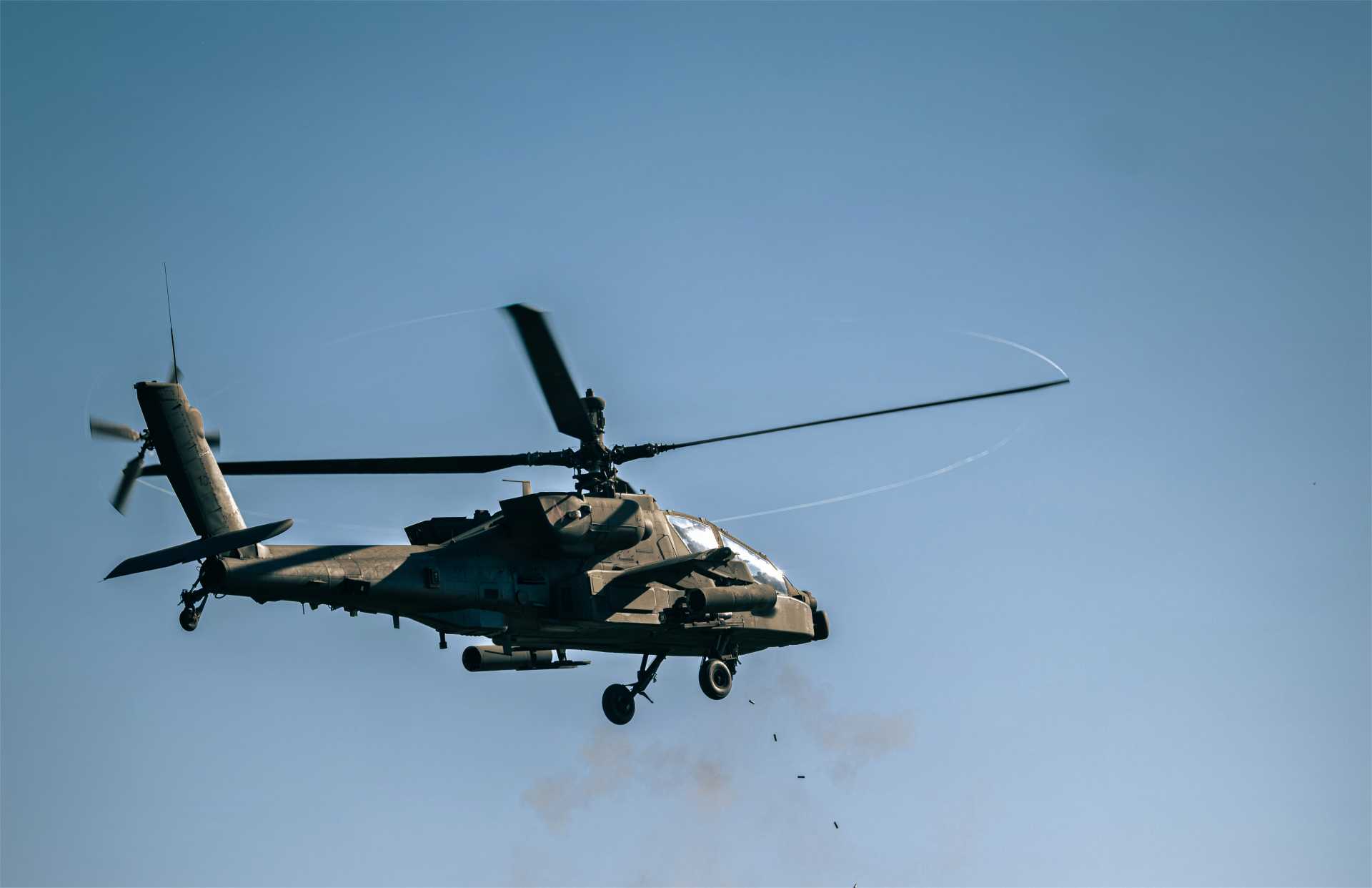 A U.S. Army AH-64 Apache from the 12th Combat Aviation Brigade fires its 30 mm chain gun during Operation Skyfall II at Grafenwoehr Training Area, Germany, on October 6, 2026. In the foreground, an AN/MPQ-64 Sentinel radar assigned to the 52nd Air Defense Artillery Brigade tracks the aerial target, supporting the helicopter’s counter-drone engagement. (Picture source: U.S. Department of War/Defense)