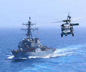 U.S. Navy USS Donald Cook (DDG 75) transits the Arabian Sea alongside an MH-60S Seahawk as U.S. forces intensify maritime interdiction operations against Iran, with CENTCOM reporting five commercial vessels diverted and one disabled as of July 18, 2026.